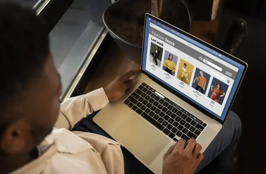 A man using a laptop to shop for clothes at an online clothing store.