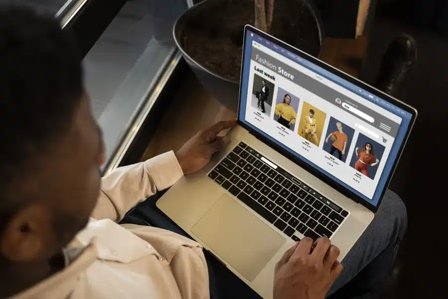 A man using a laptop to shop for clothes at an online clothing store.